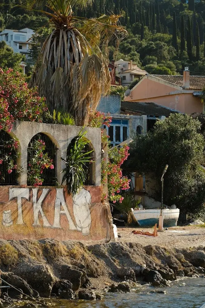 woman sunbathing on a rocky beach with houses and hills behind her