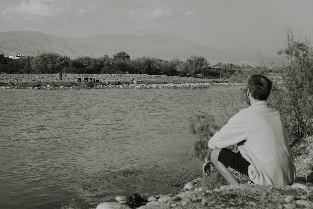 man sitting alone near a lake