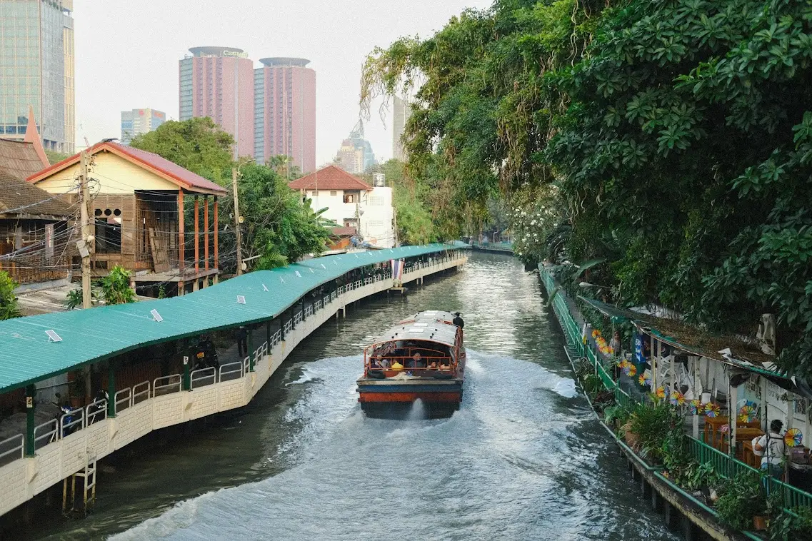 boat crossing bangkok canals with the tall buildings in the background