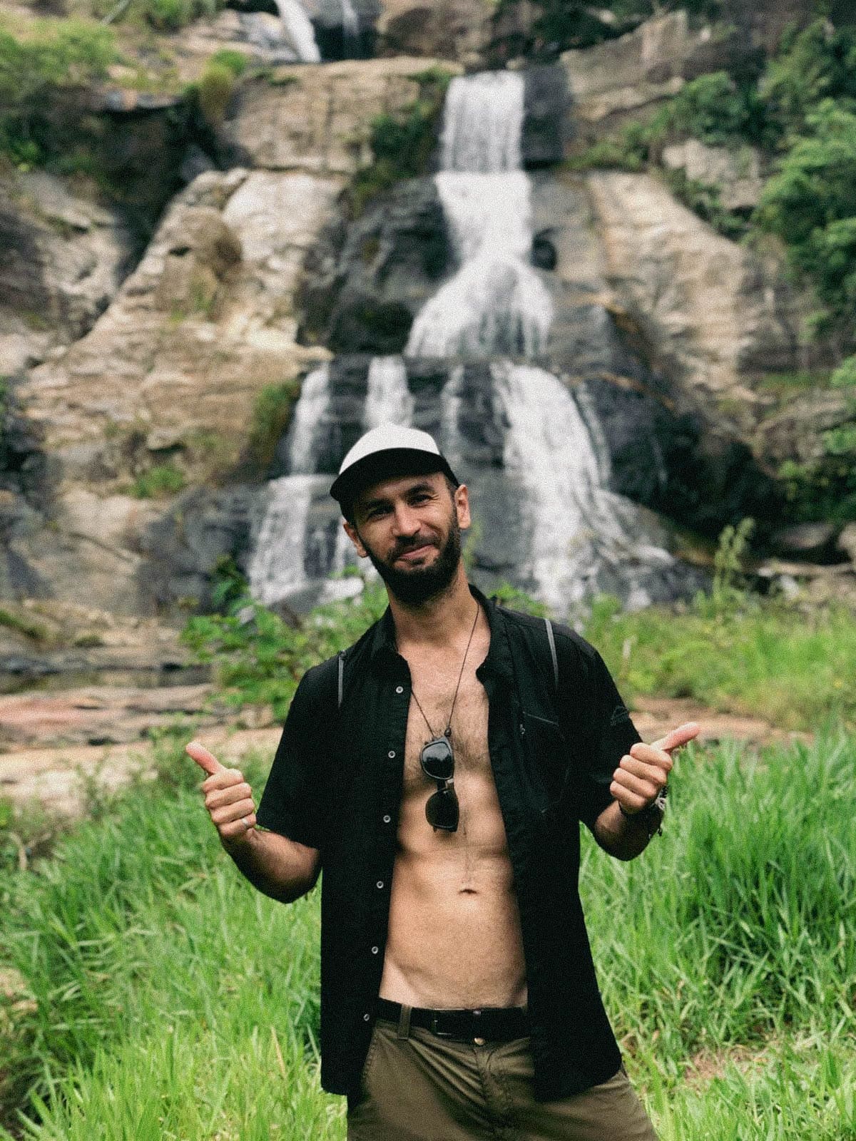 man is photographed in front of a waterfall in the jungle of Sri Lanka