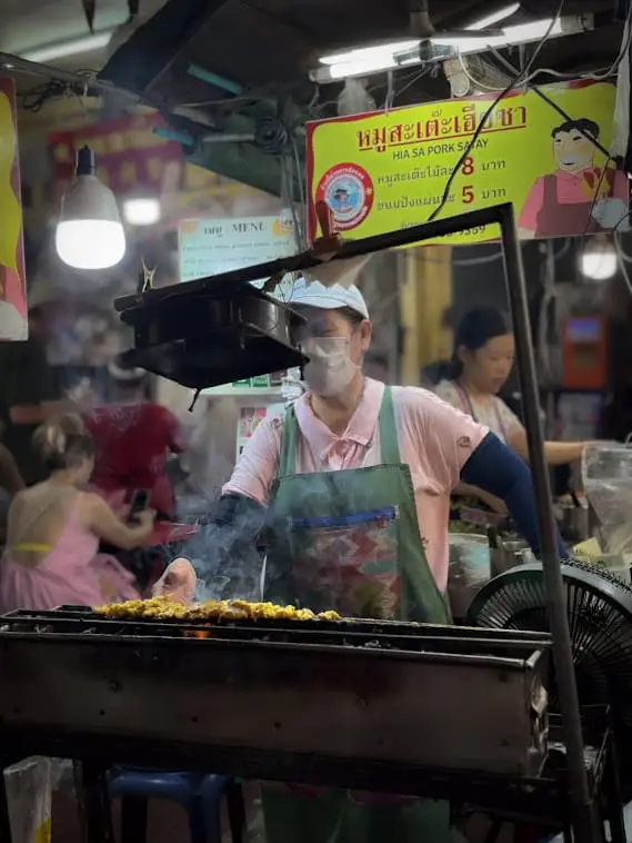 bangkok street food vendor grilling pork satay