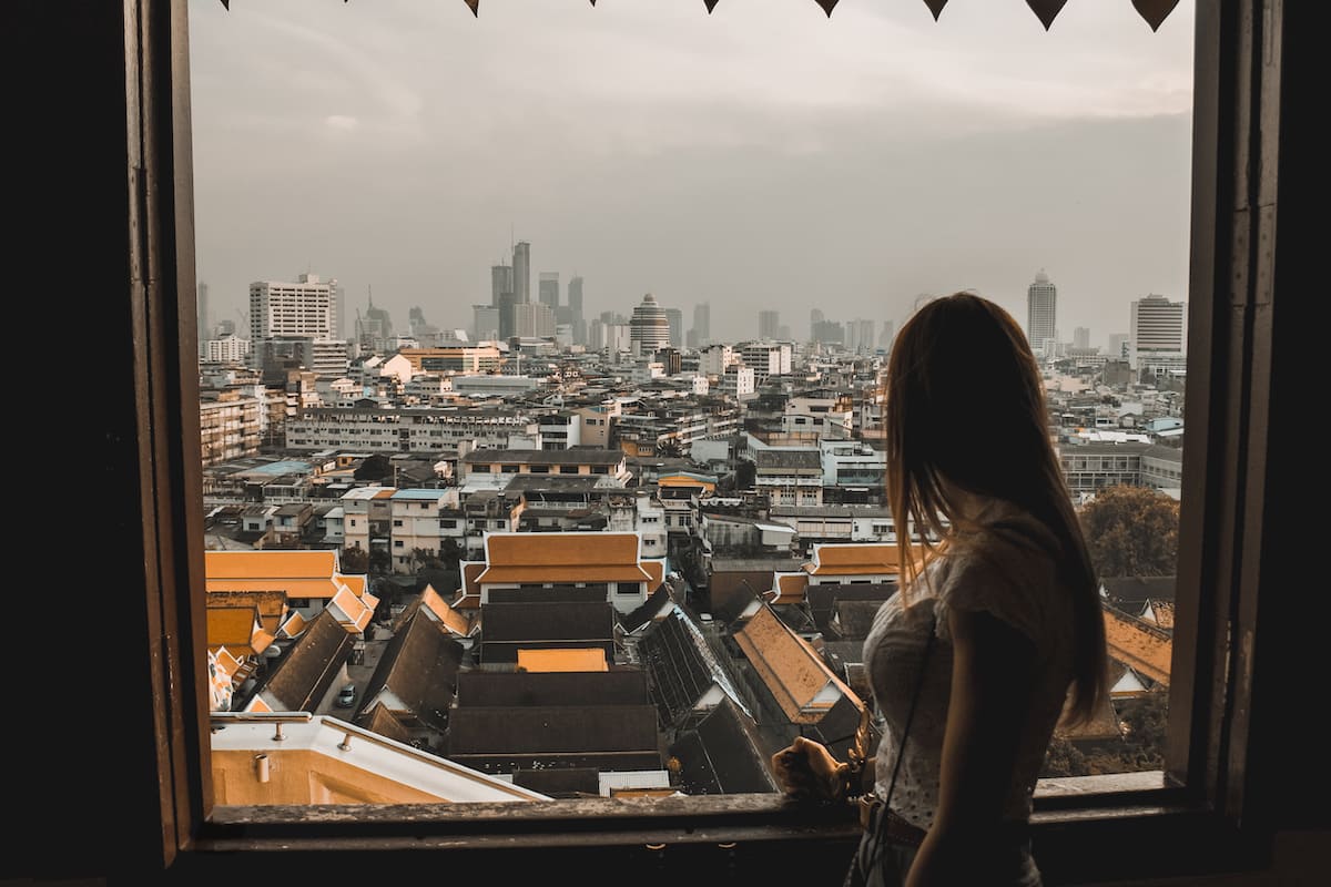 girl looking from a big window facing bangkok from above